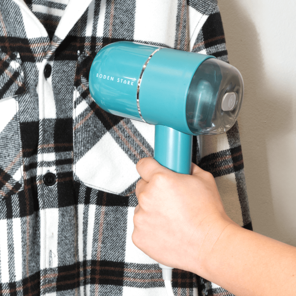 Boden Stark Handheld Steamer in use, easily removing wrinkles from a plaid shirt, perfect for quick touch-ups.