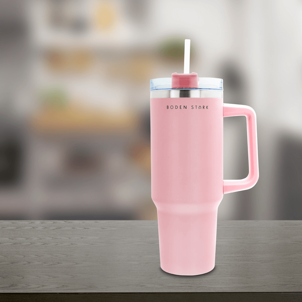 Boden Stark 1200ml pink travel mug on a wooden table with a blurred background, perfect for travel and on-the-go use.