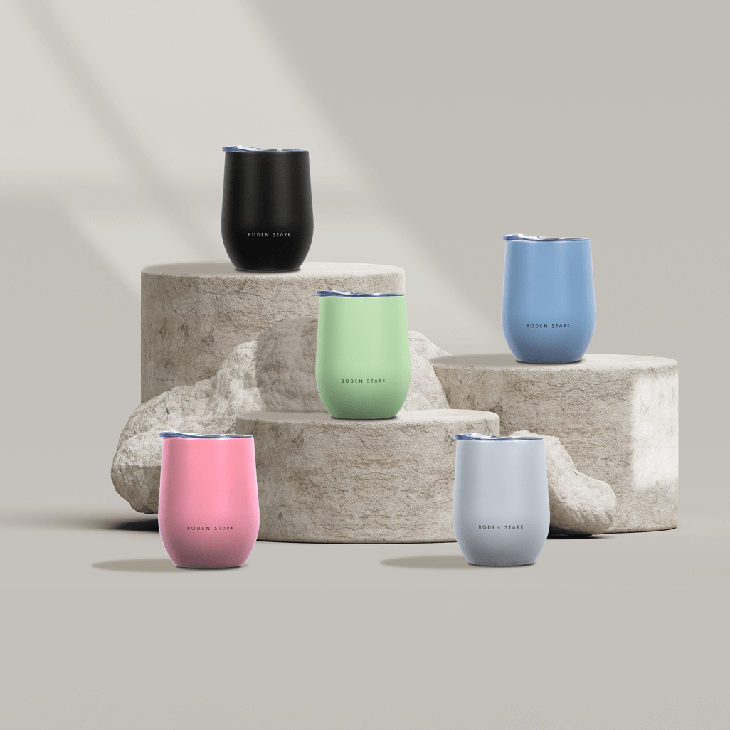 Boden Stark 350ml tumblers in green, pink, blue, black, and light blue displayed on stone pedestals.