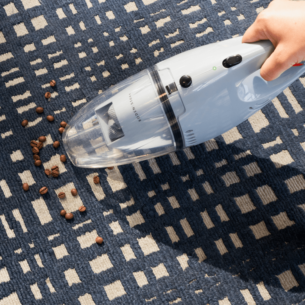 Boden Stark Handheld Vacuum Cleaner removing coffee beans from a patterned rug.
