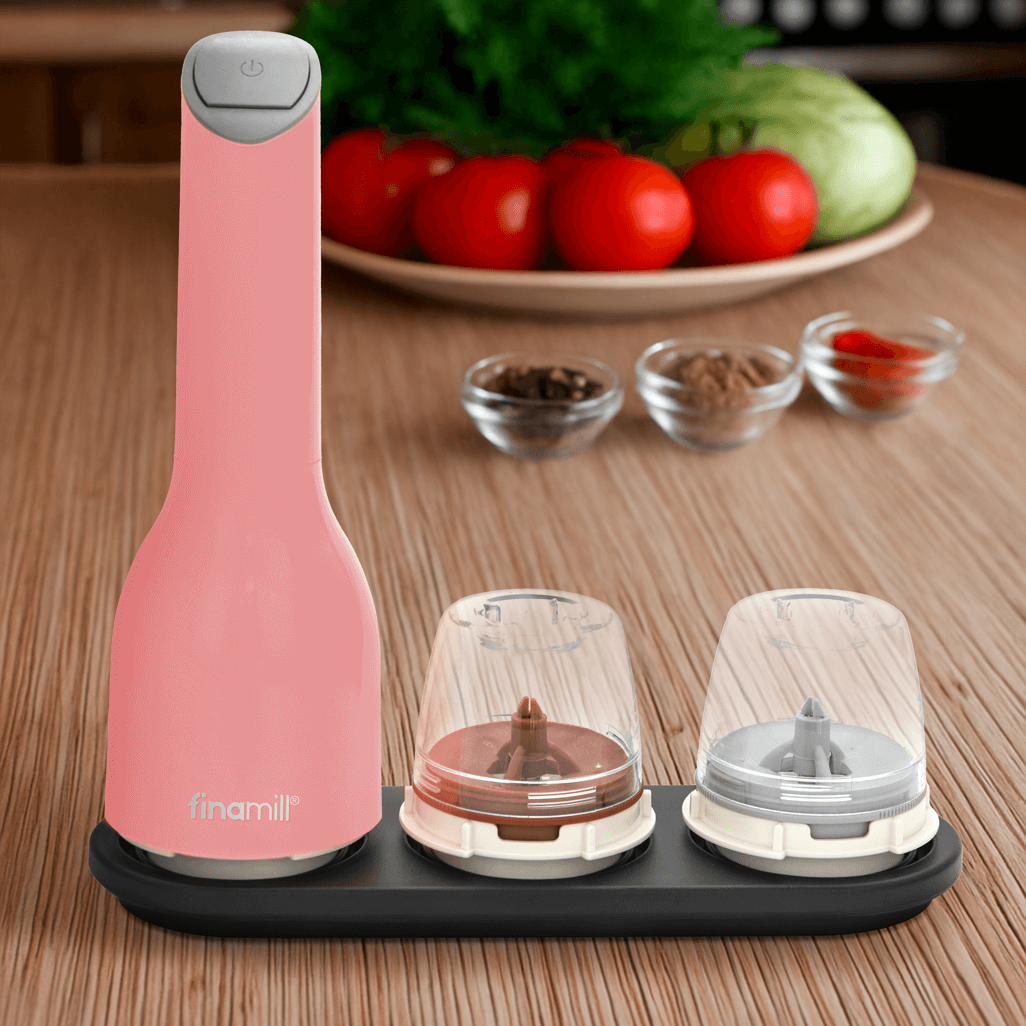 FINAMILL battery operated grinder in pink on a kitchen counter with spice containers neatly arranged.
