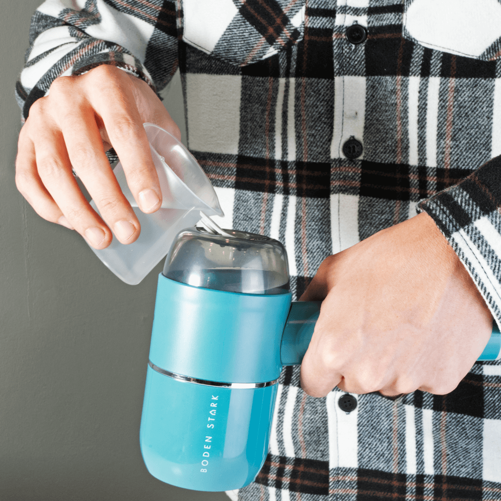 Person pouring water into Bodens Stark Handheld Steamer, demonstrating its convenient use.