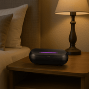 Zen Radiant Diffuser in black placed on a nightstand near a lamp, creating a calming atmosphere.