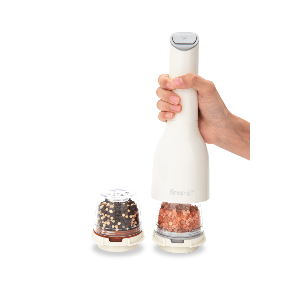 FINAMILL battery-operated grinder in soft cream with spices, hand holding the device next to spice containers.