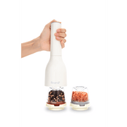 FINAMILL battery-operated grinder in soft cream, held by hand, with pepper and salt containers beside it.