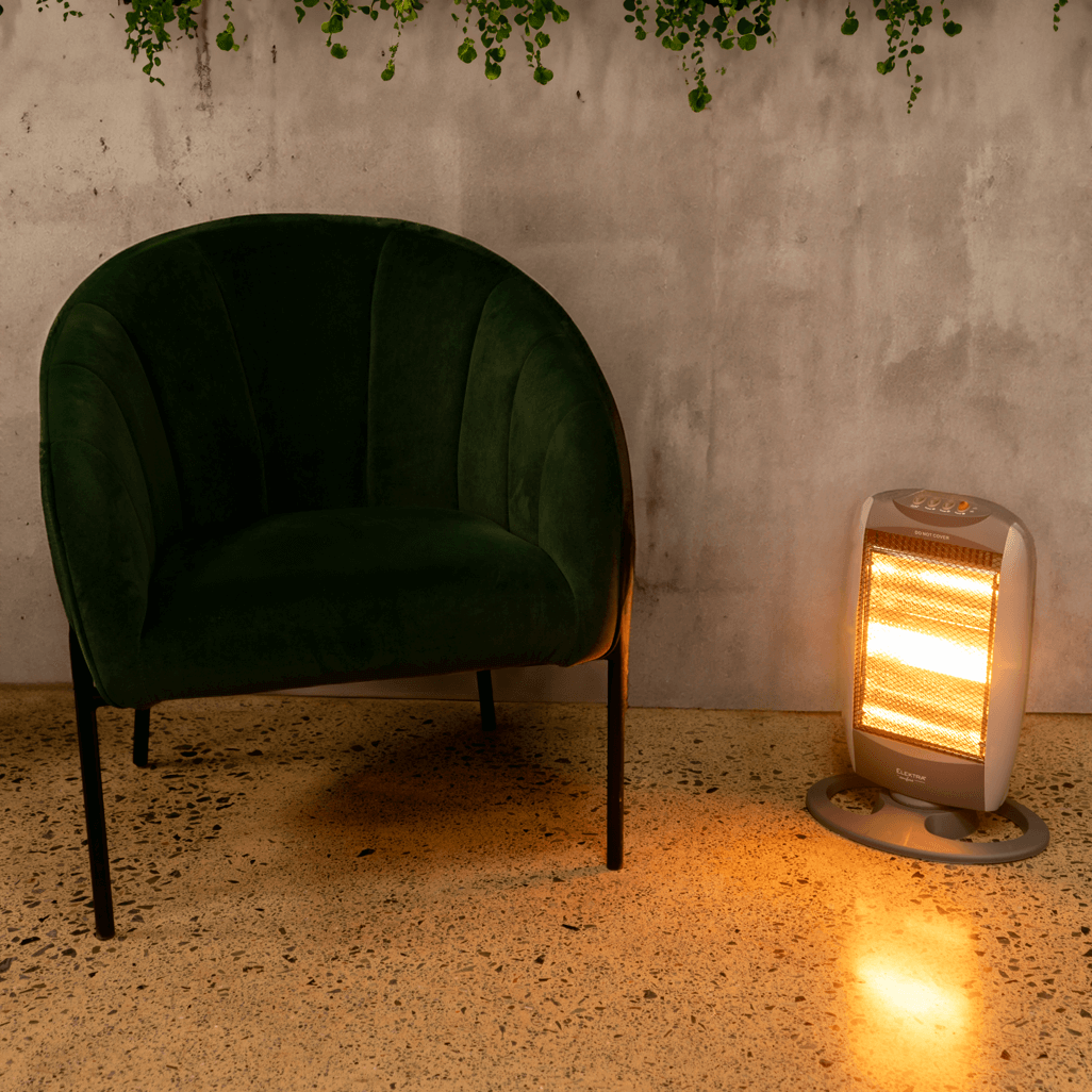Stylish green chair next to the ELEKTRA 3 Bar Halogen Heater, providing warmth in a modern indoor setting.