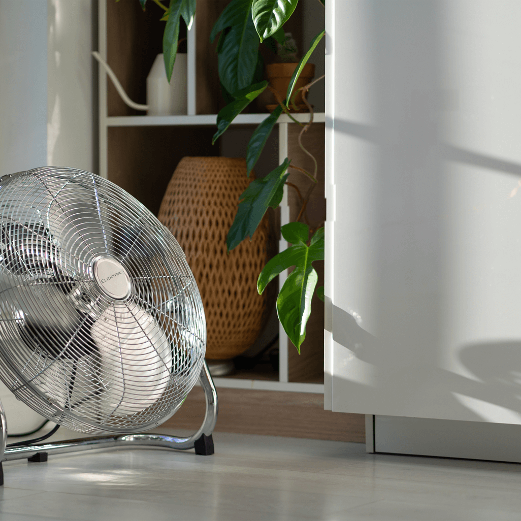 Elektra Power Fan in a bright room, beside a potted plant and decorative items, providing a stylish cooling solution.