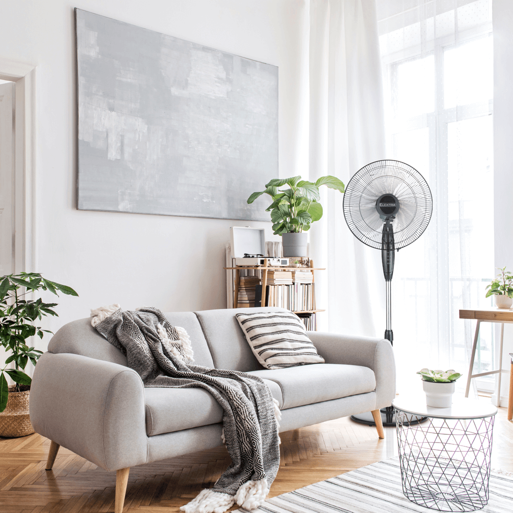 Elektra stand fan in a stylish living room with a gray couch, plants, and natural light filtering through curtains.