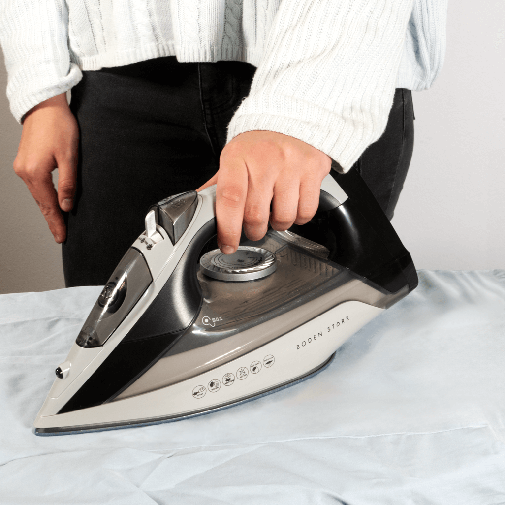 Boden Stark 2200W Ceramic Steam Iron in use, effectively smoothing a light blue fabric during ironing.