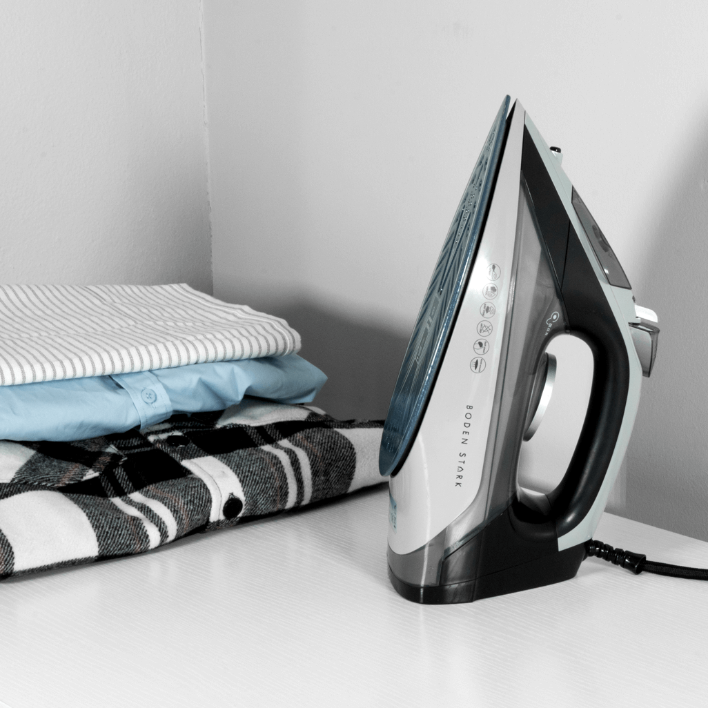 Boden Stark 2200W Ceramic Steam Iron next to neatly folded shirts on a table.