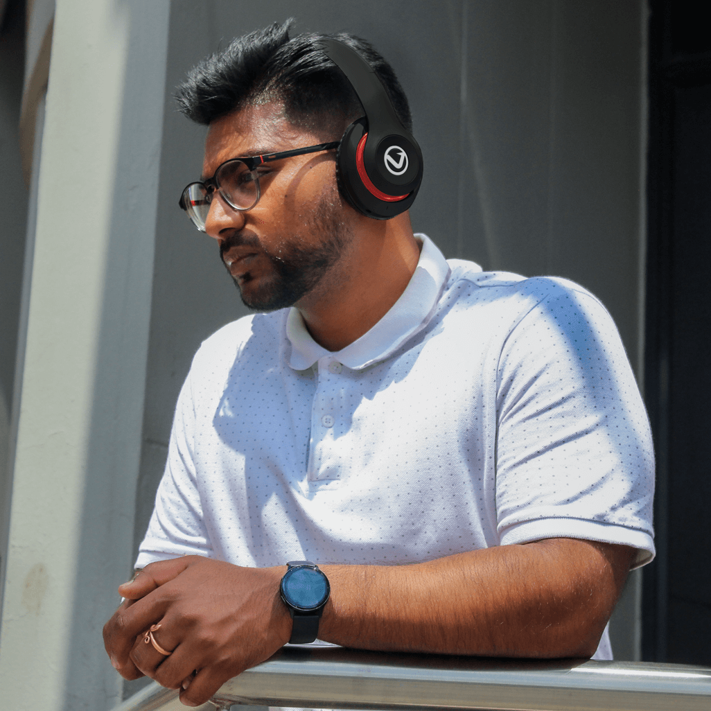 Man wearing Volkano Impulse Series Bluetooth headphones in black, enjoying music outdoors with a casual outfit.