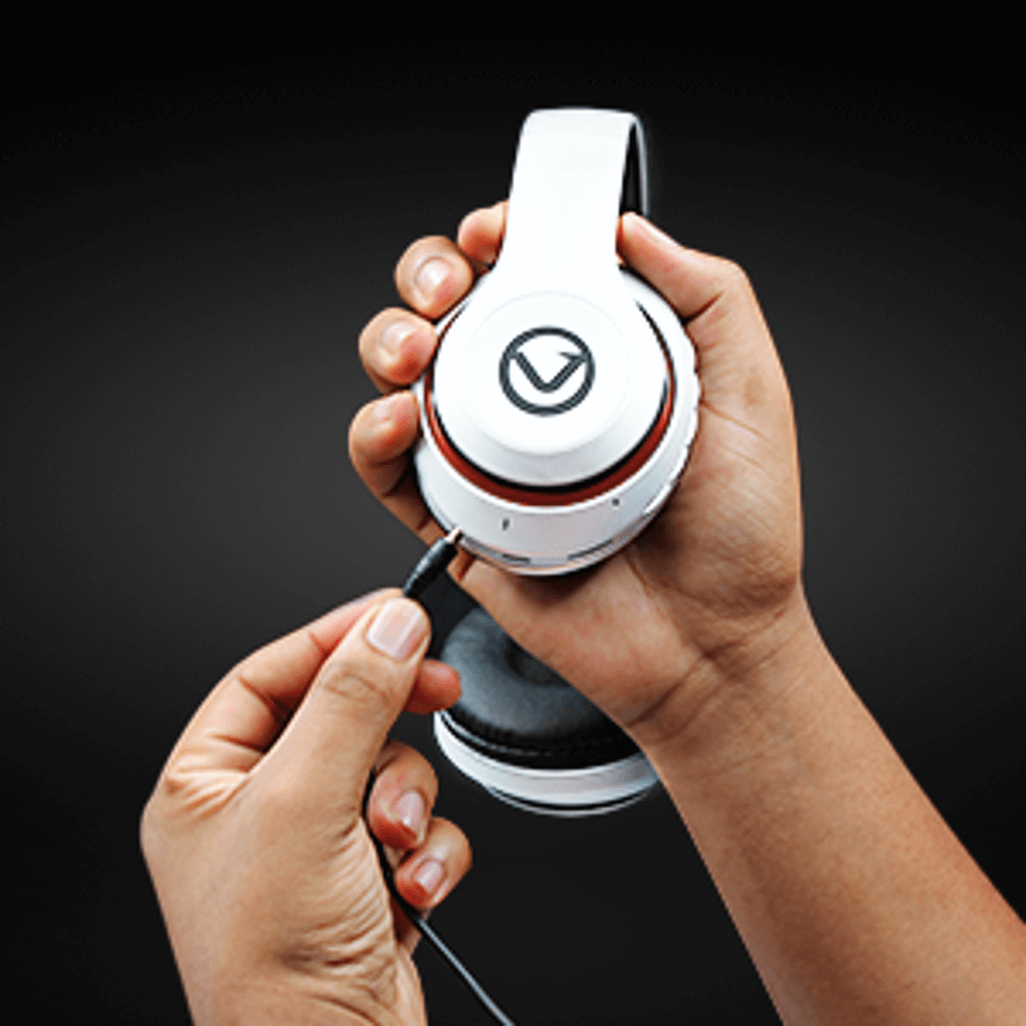Person connecting a cable to Volkano Impulse Series Bluetooth Headphones in white against a black background.