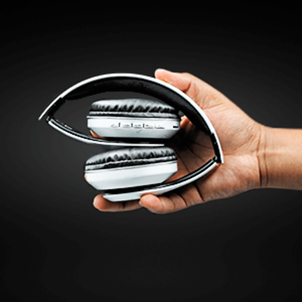 Person holding folded Volkano Impulse Series Bluetooth Headphones in a sleek design, showcasing portability and style.