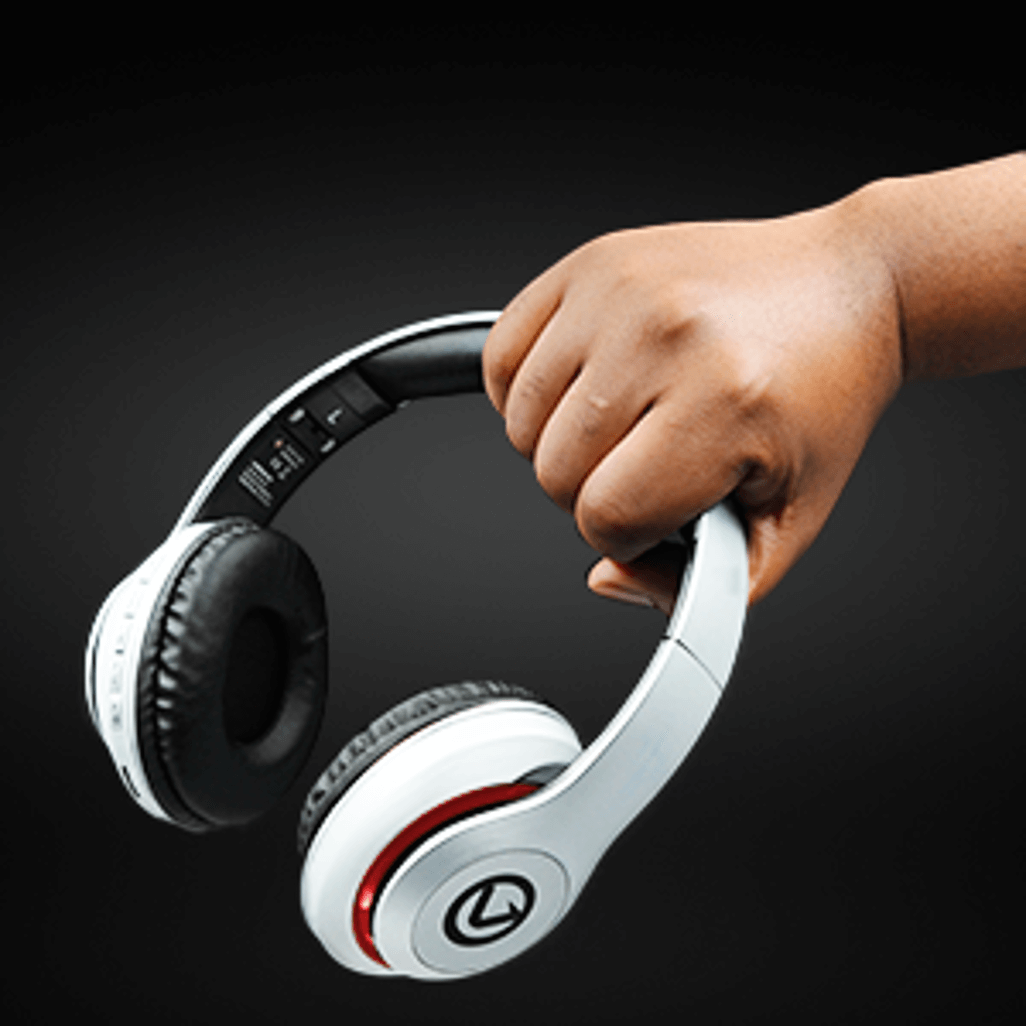 Hand holding Volkano Impulse Series Bluetooth Headphones in white with black ear cushions.