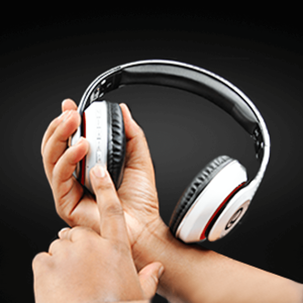 Person adjusting volume on Volkano Impulse Series Bluetooth Headphones - White, showcasing ergonomic design.