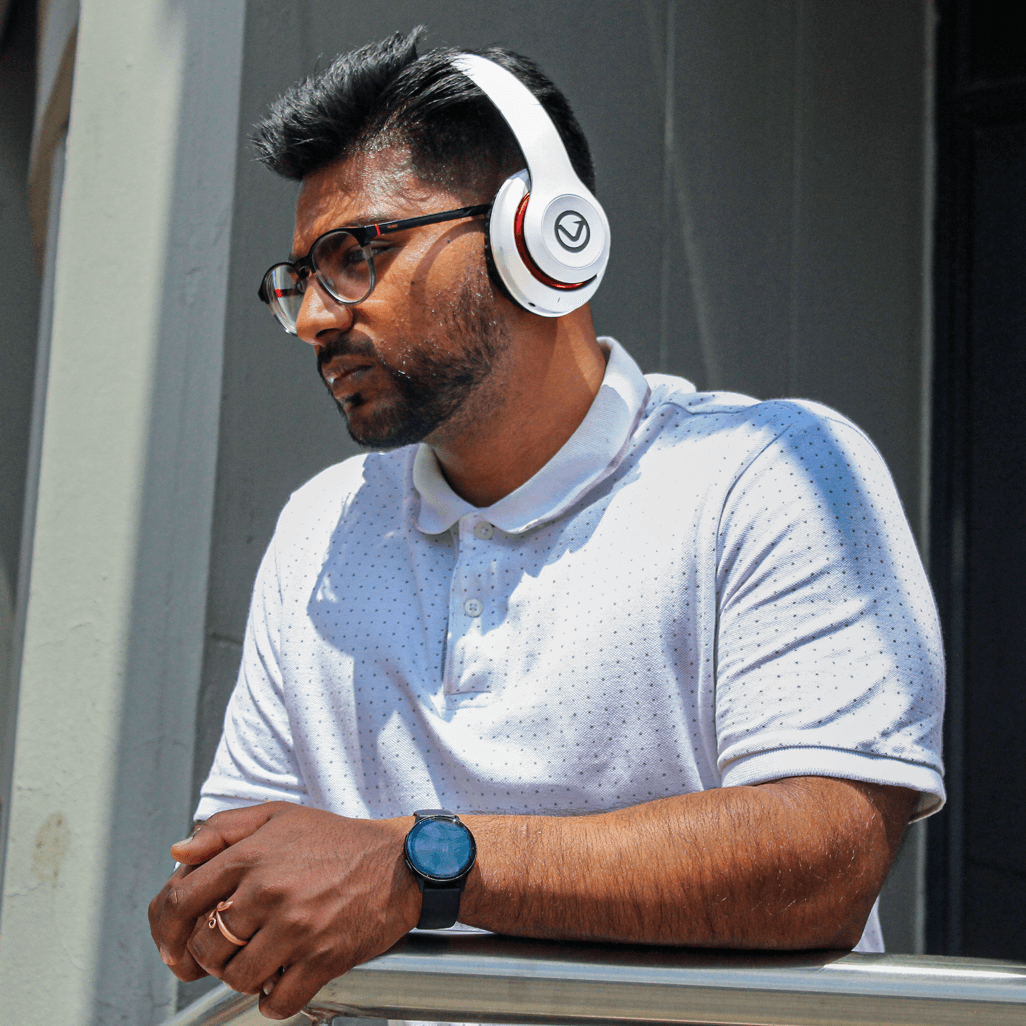 Man wearing Volkano Impulse Series Bluetooth Headphones in white, enjoying music outdoors.